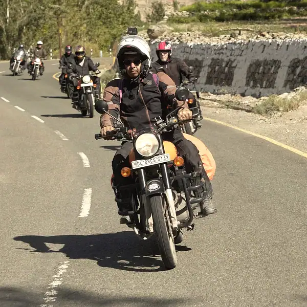 Motorcycle riders enjoying a scenic mountain road with lush greenery and clear skies.